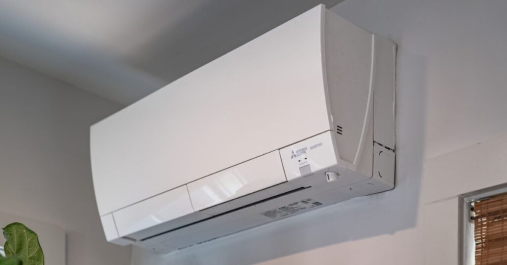 A ductless air conditioner installed adjacent to a window on a white wall. The number '27' is displayed on the unit.